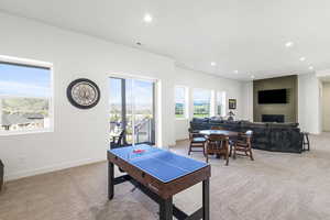 Open-concept recreation area featuring multiple large windows, sliding glass door access to an outdoor space, recessed lighting, and a textured accent wall with a fireplace