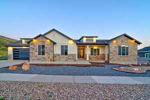 Contemporary ranch-style exterior featuring a stone and board-and-batten facade, a modern garage door, and a low-maintenance gravel and rock landscape