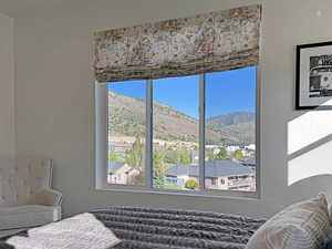 Expansive window featuring a floral roman shade and mountain scenery