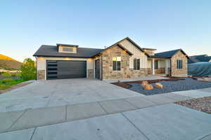 Modern residential exterior featuring stone veneer, vertical siding accents, and a dark asphalt shingle roof