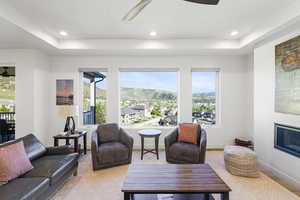 Bright living space featuring multiple large windows showcasing a mountain and community backdrop