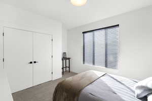 Bright bedroom featuring neutral wall tones, a large window with horizontal blinds, textured carpet flooring, and a ceiling-mounted light fixture