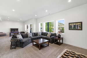 Spacious carpeted living area featuring recessed lighting, multiple windows providing natural illumination, and a light-colored wall finish