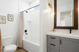 Bathroom featuring a tub/shower combination with black fixtures, a white vanity countertop, gray cabinetry, and wood-finish flooring