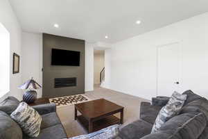 Living area featuring a modern linear fireplace with a dark accent wall, recessed lighting, and light-toned carpeting