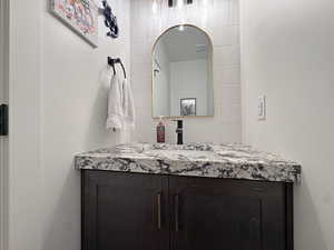 Bathroom vanity with a dark wood-finish cabinet, speckled stone countertop, and integrated sink