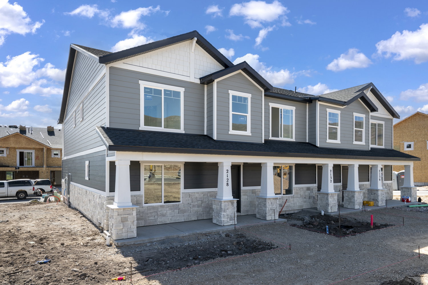 Modern townhome exterior featuring grey siding and white stone veneer