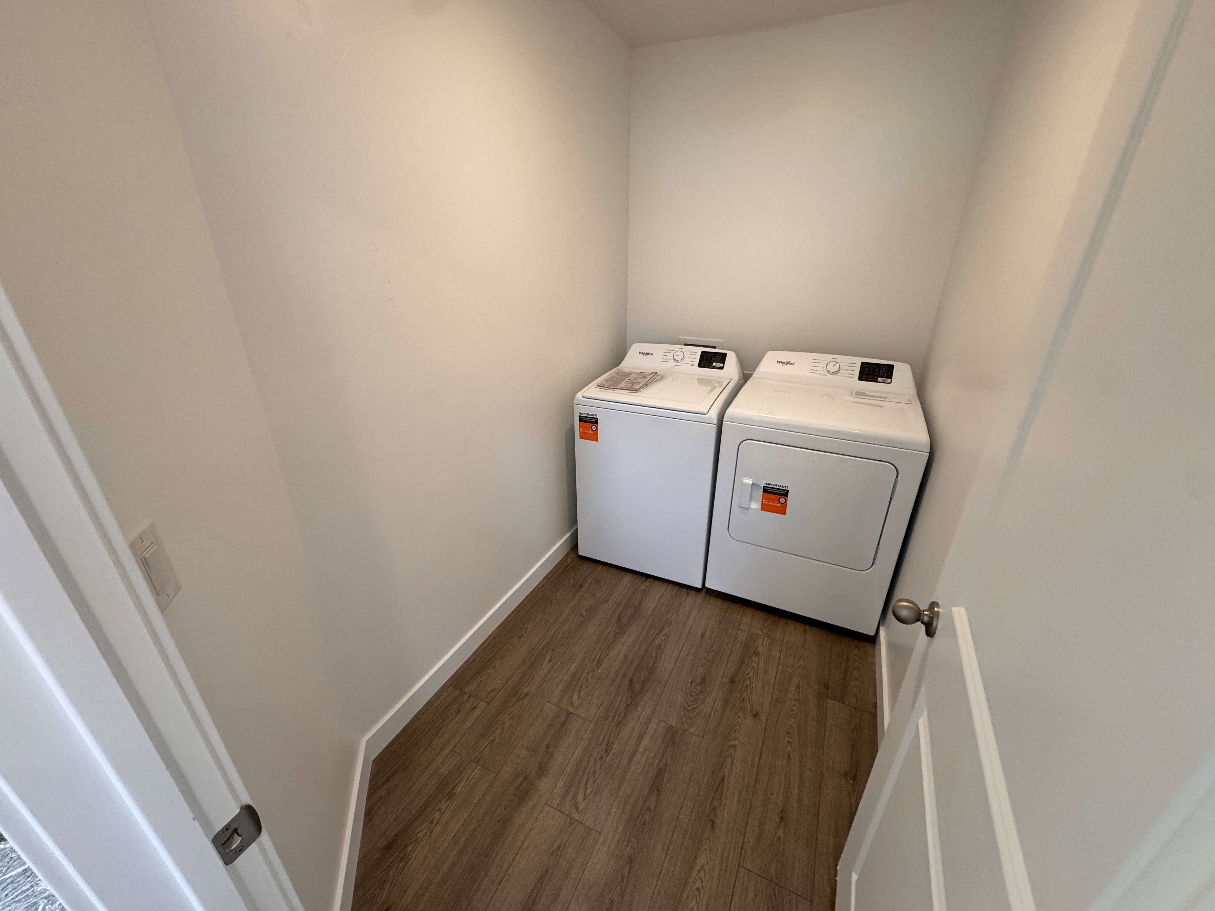 Dedicated laundry area featuring wood-finish flooring and crisp white walls