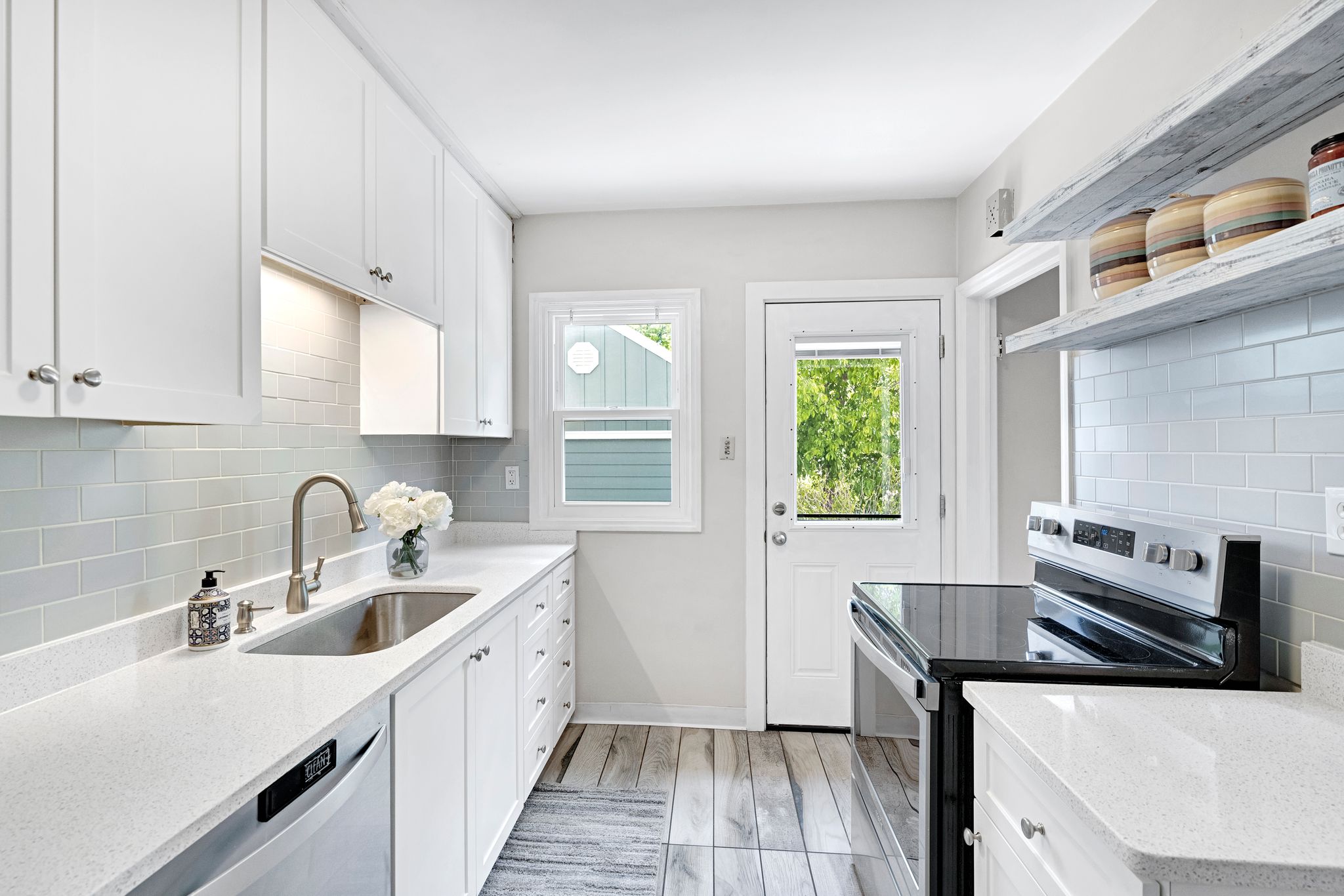 Kitchen featuring white cabinetry, light-toned countertops, a stainless steel sink with a gooseneck faucet, and a light-colored subway tile backsplash