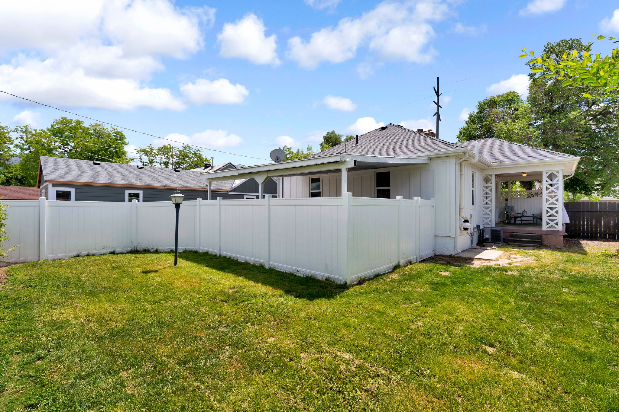 Expansive grassy yard area with a white privacy fence