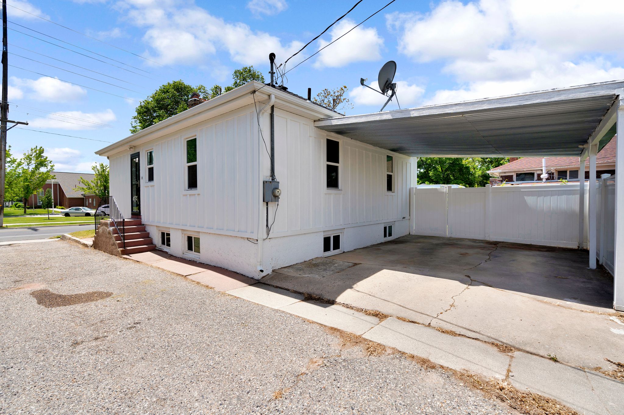 White vertical siding exterior featuring a covered carport