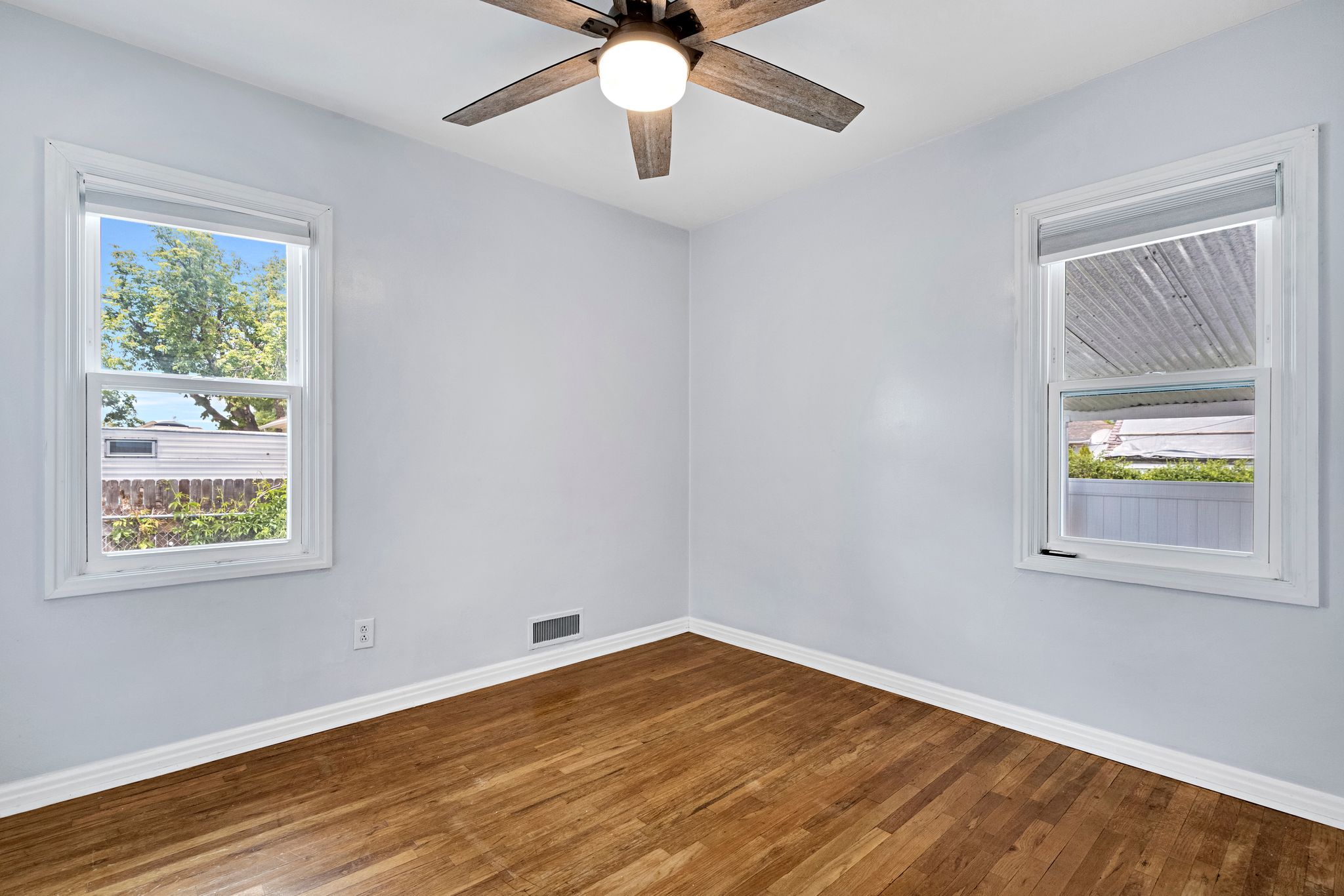 Room featuring wood-finish flooring, light gray wall paint, and white baseboards