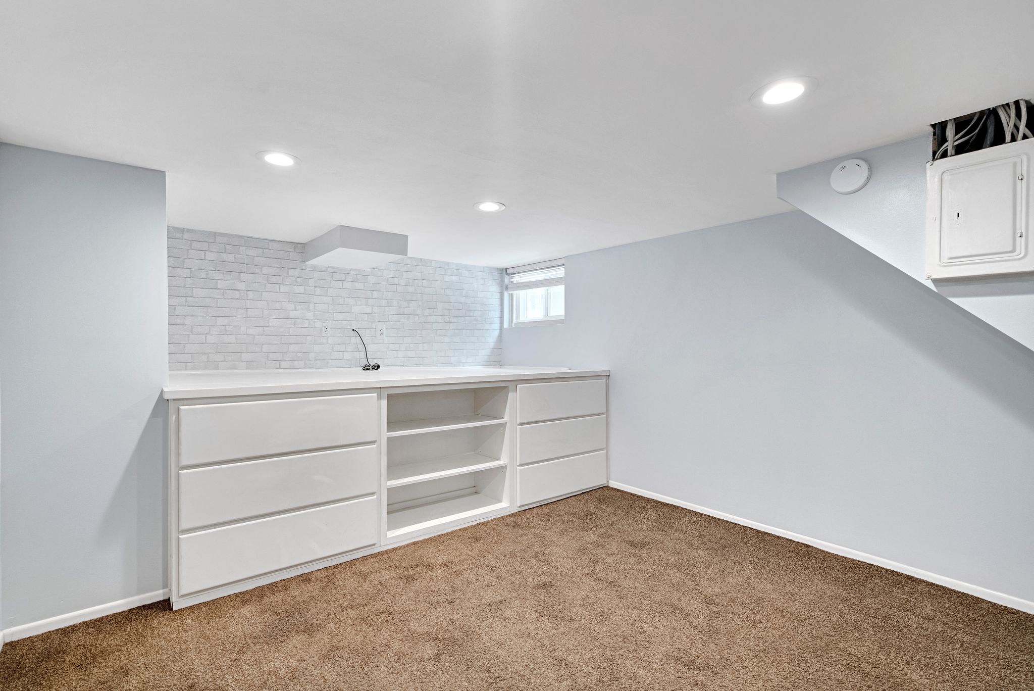 Integrated white cabinetry with open shelving and drawers, complemented by a solid surface countertop and a white subway tile backsplash