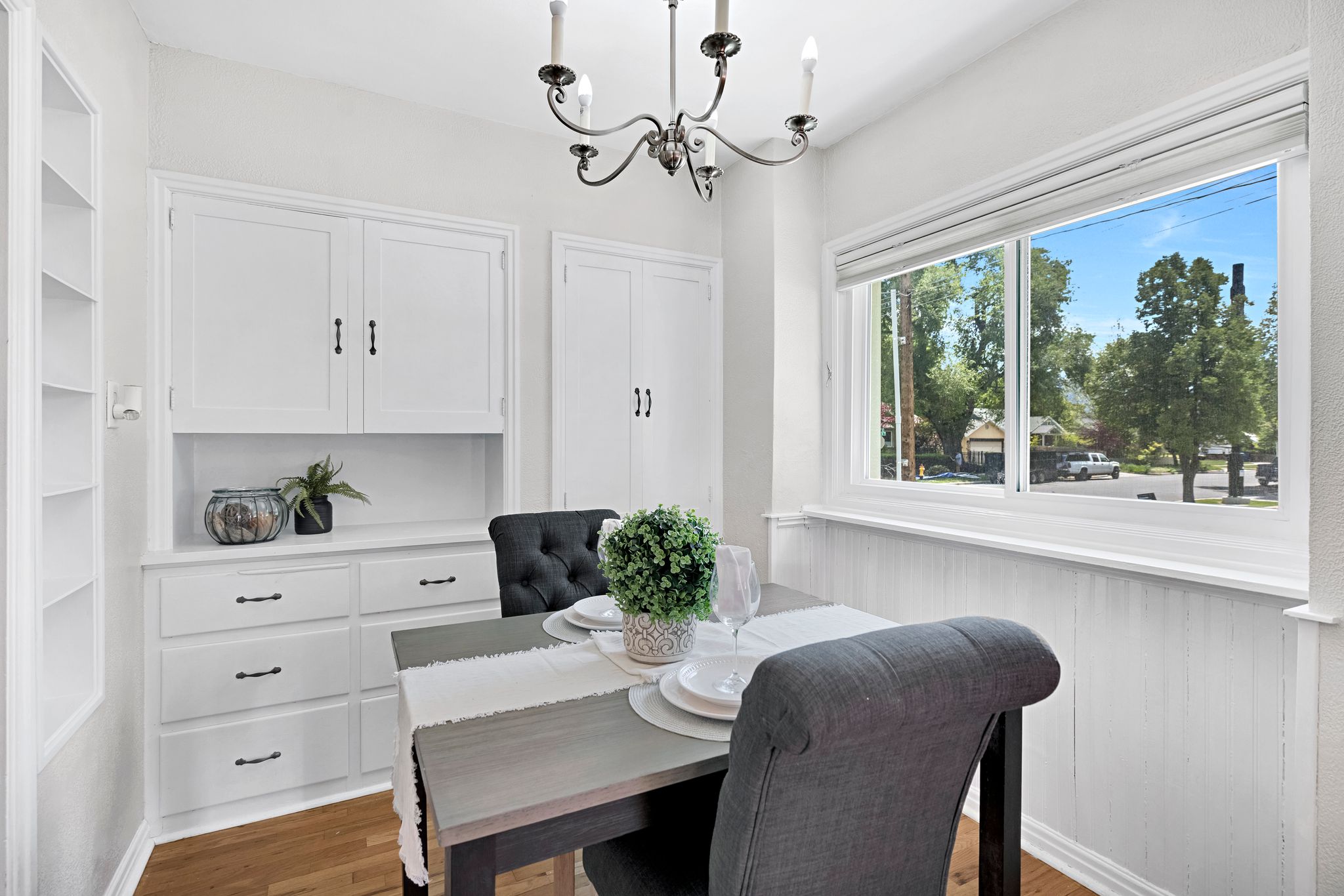 Dining area featuring integrated white cabinetry with dark hardware, a built-in shelving unit, and wood-finish flooring