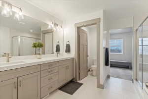 Spacious bathroom featuring a dual vanity with light-toned cabinetry and brushed nickel hardware, expansive mirror, and a glass-enclosed shower