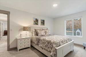 Spacious room featuring neutral carpeting, a large window, recessed lighting, and a doorway with contrasting trim