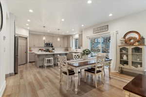 Spacious kitchen and dining area with light wood-finish flooring, recessed lighting, and a sliding glass door