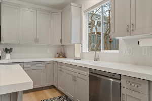 Contemporary kitchen featuring light gray cabinetry, white countertops, and a full-height tile backsplash