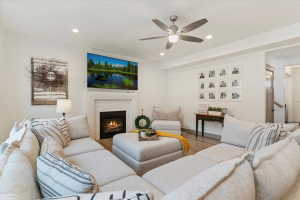 Living area featuring a white brick-surround fireplace with a white mantel, recessed lighting, a ceiling fan, and wood-finish flooring