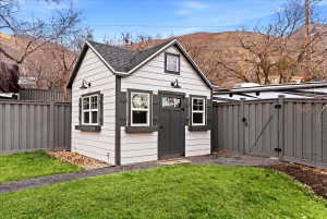 Detached storage shed with gable roof, white siding, dark trim, and decorative exterior lighting