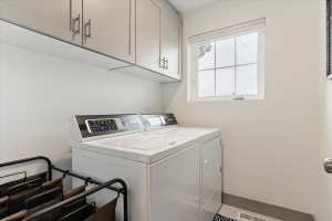 Dedicated laundry space featuring upper cabinetry, a transom window, and tiled flooring