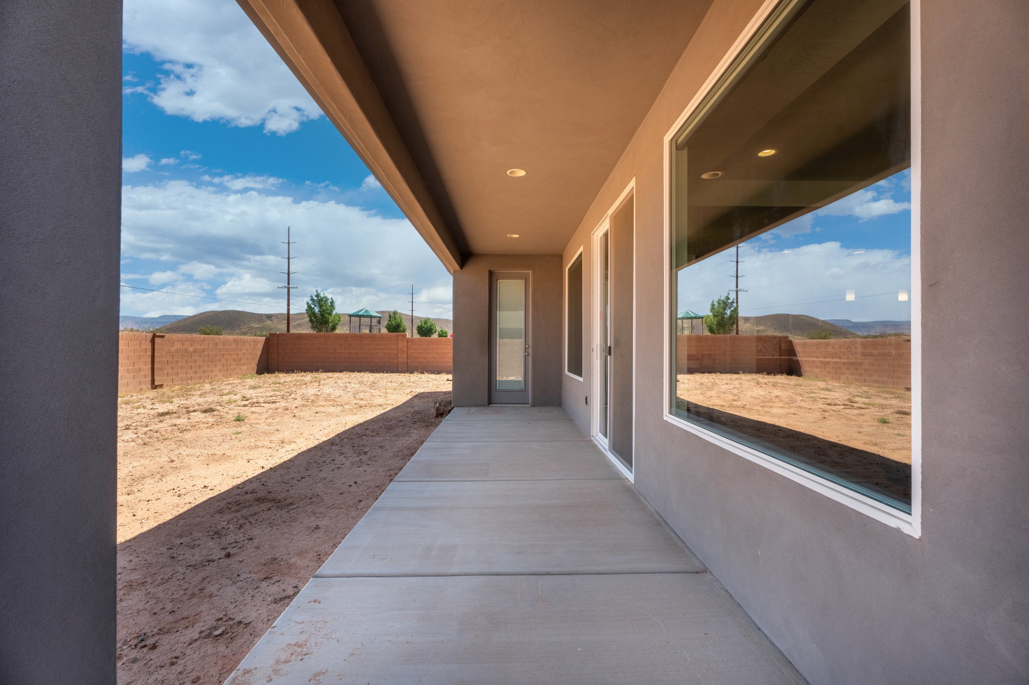 Rear patio featuring a concrete slab, stucco exterior, and large windows