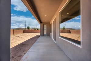 Rear patio featuring a concrete slab, stucco exterior, and large windows