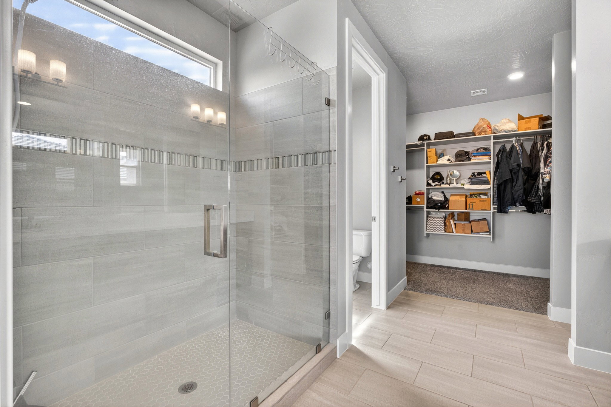 Walk-in shower with clear glass enclosure and light-toned tilework