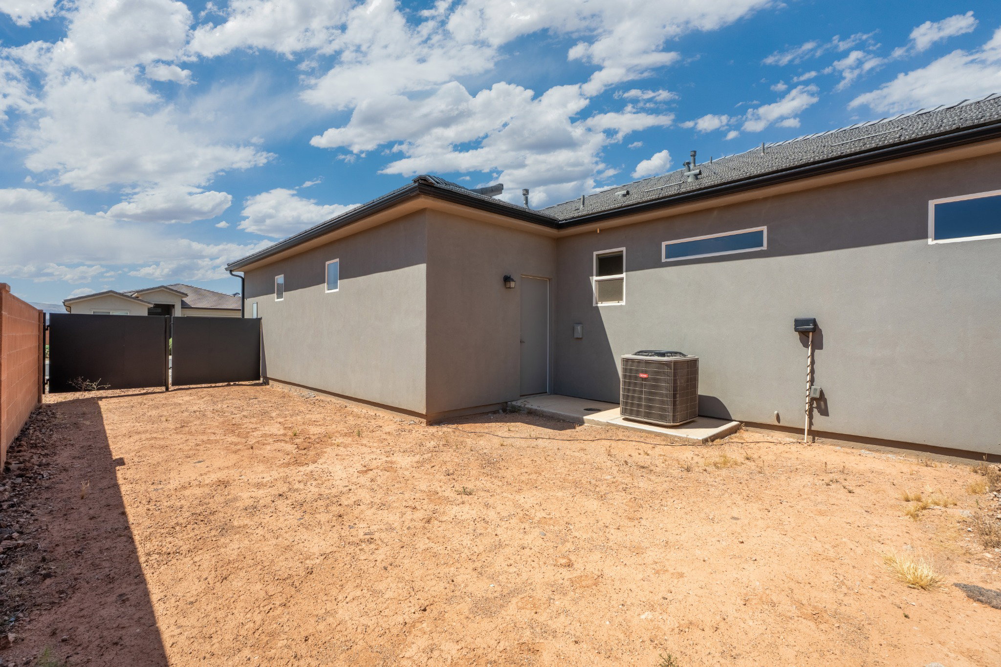 Rear exterior with stucco finish and a gravel/dirt yard area