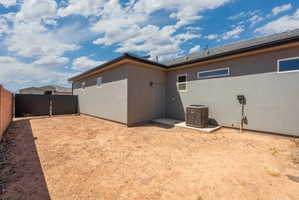 Rear exterior with stucco finish and a gravel/dirt yard area