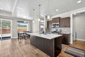 Contemporary kitchen featuring a spacious island with a white countertop, dark wood-finish cabinetry, and a mosaic tile backsplash