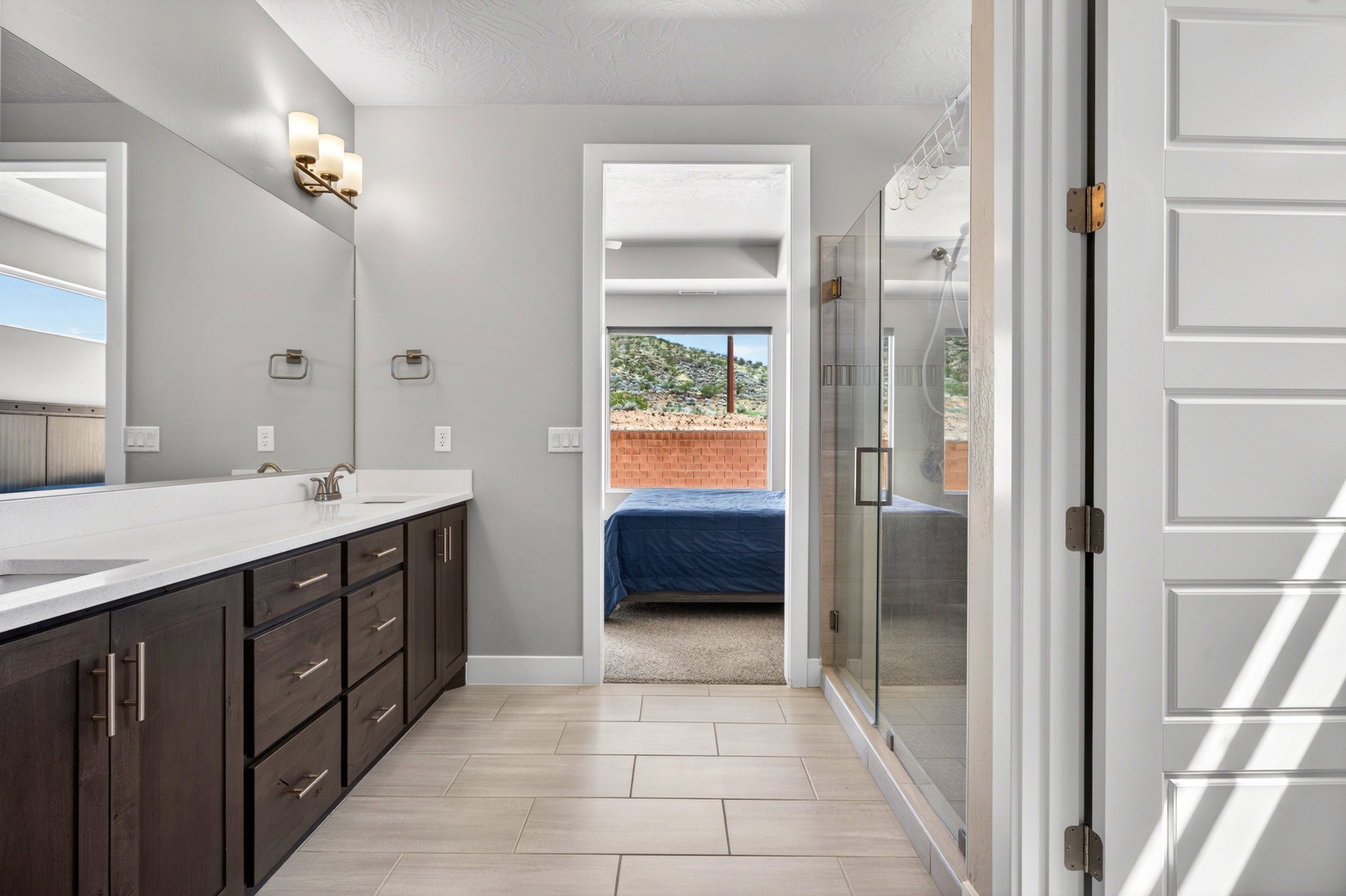 Dual sink vanity with dark wood-finish cabinetry, light countertops, and brushed nickel hardware