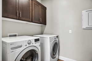 Laundry area featuring dark wood-finish cabinetry with silver hardware, light gray walls, and wood-finish flooring