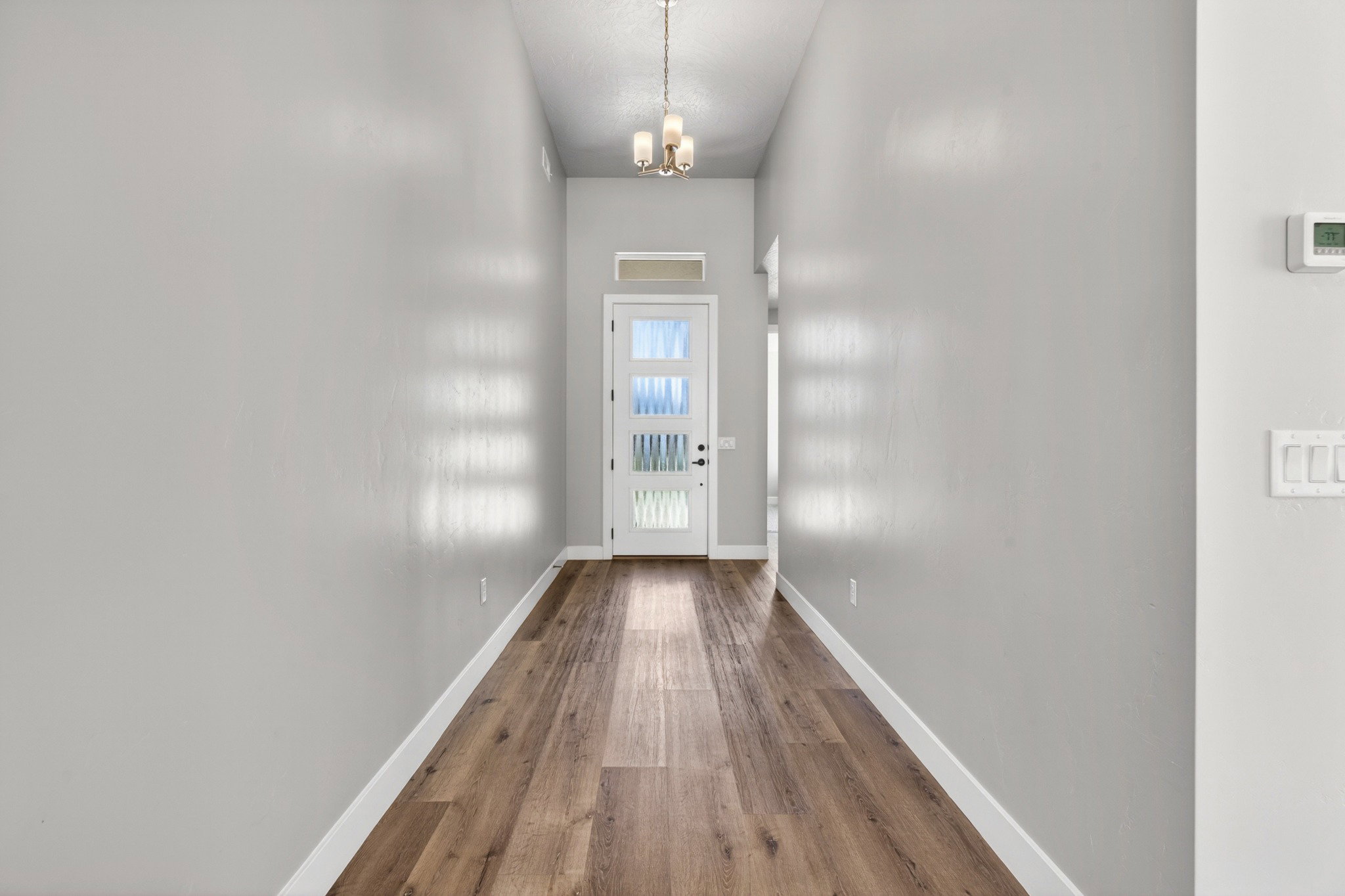 Entryway featuring wood-finish flooring, light grey walls, and a recessed ceiling with a chandelier