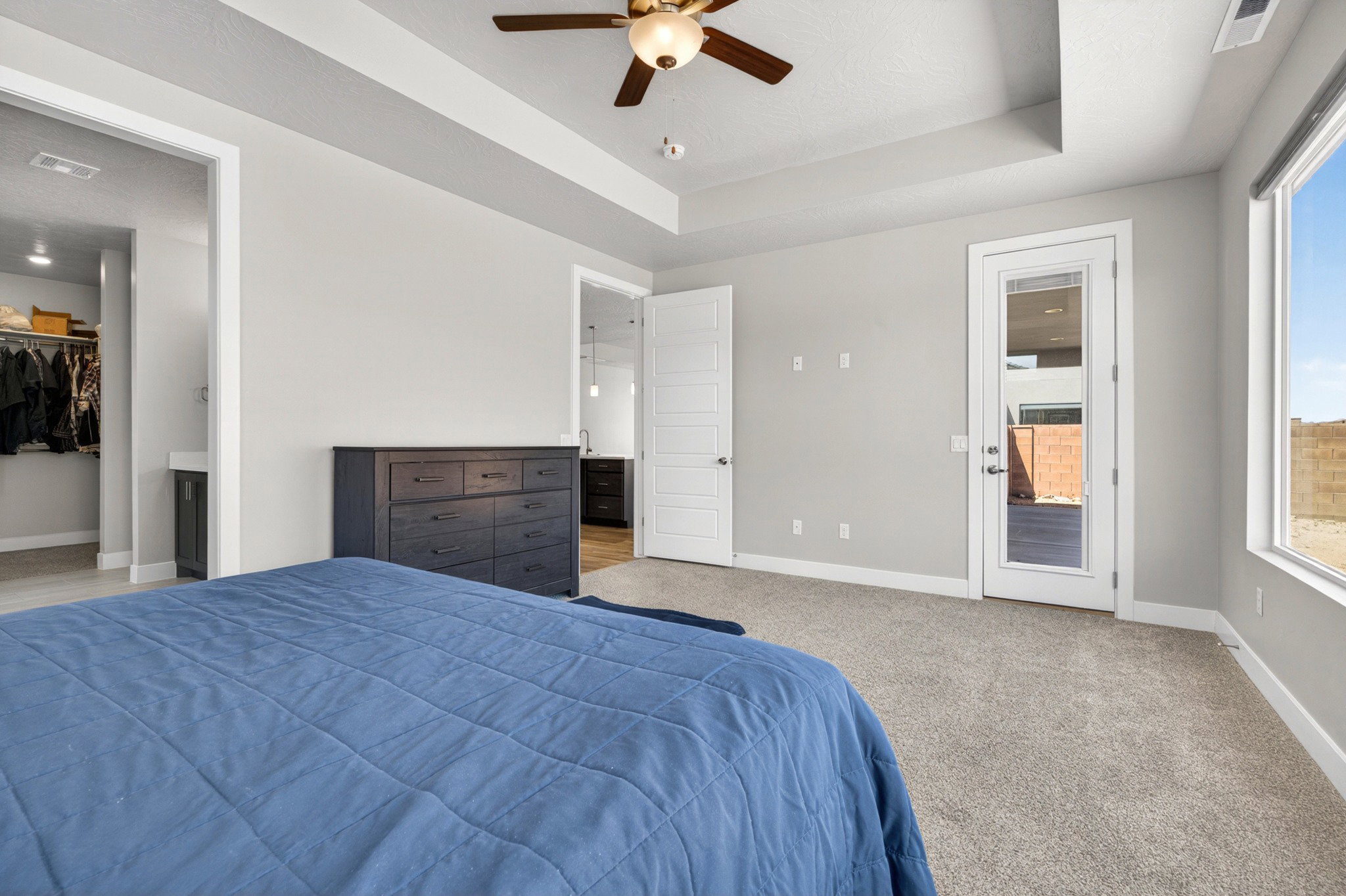 Spacious bedroom featuring light neutral wall tones and plush carpet flooring