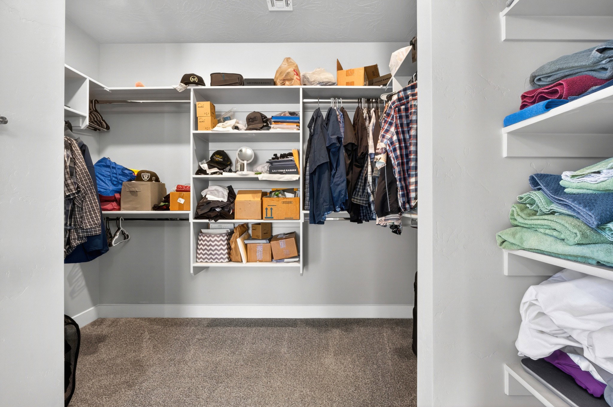 Walk-in closet featuring built-in shelving, chrome hanging rods, recessed lighting, and grey carpet flooring