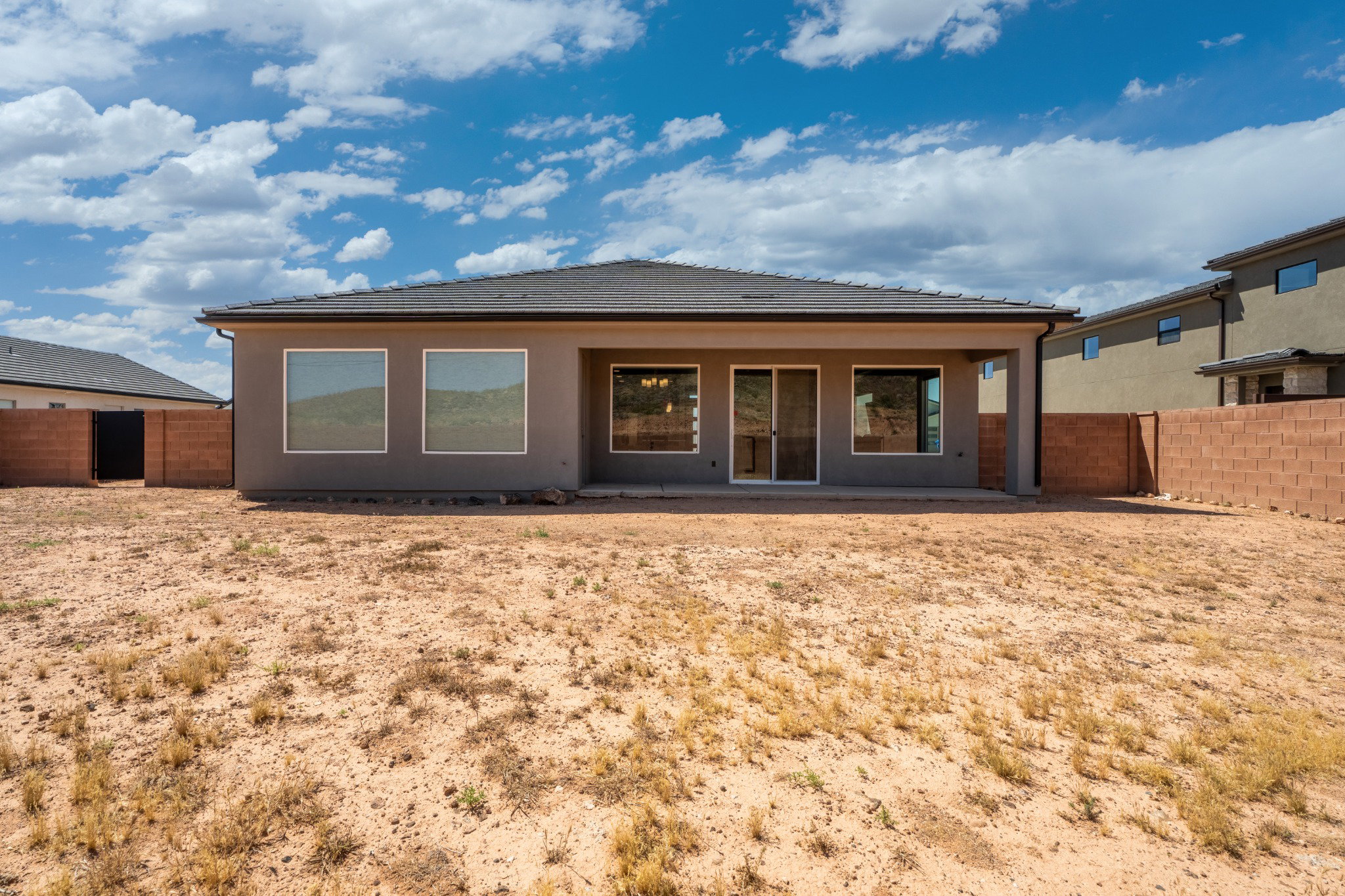 Rear exterior featuring a covered patio, multiple windows, and a sliding glass door