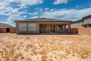 Rear exterior featuring a covered patio, multiple windows, and a sliding glass door