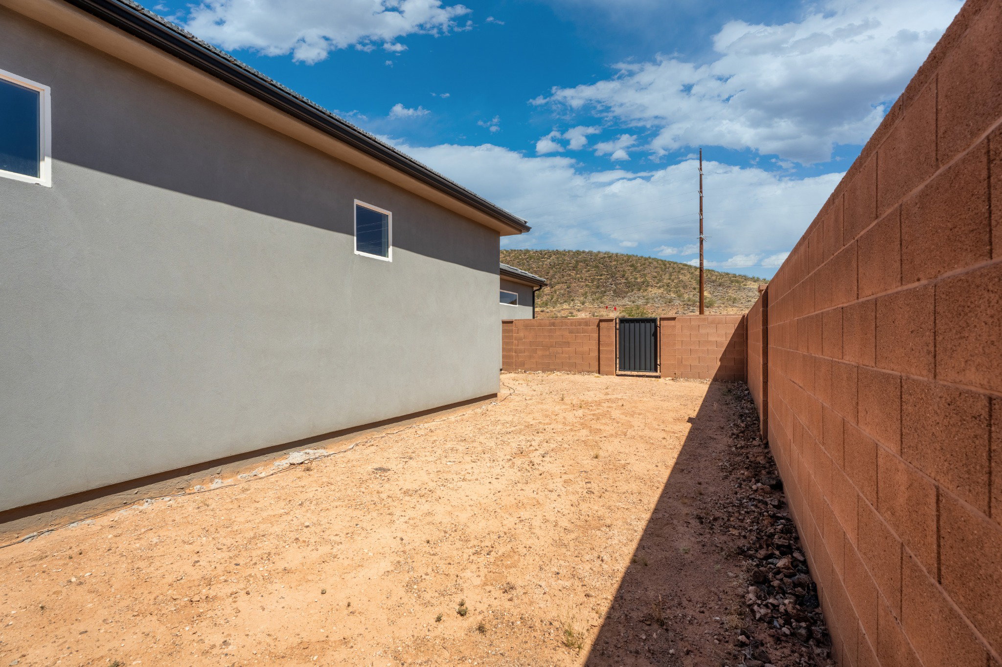 Exterior stucco siding with multiple windows, complemented by a block wall perimeter and a rear gate