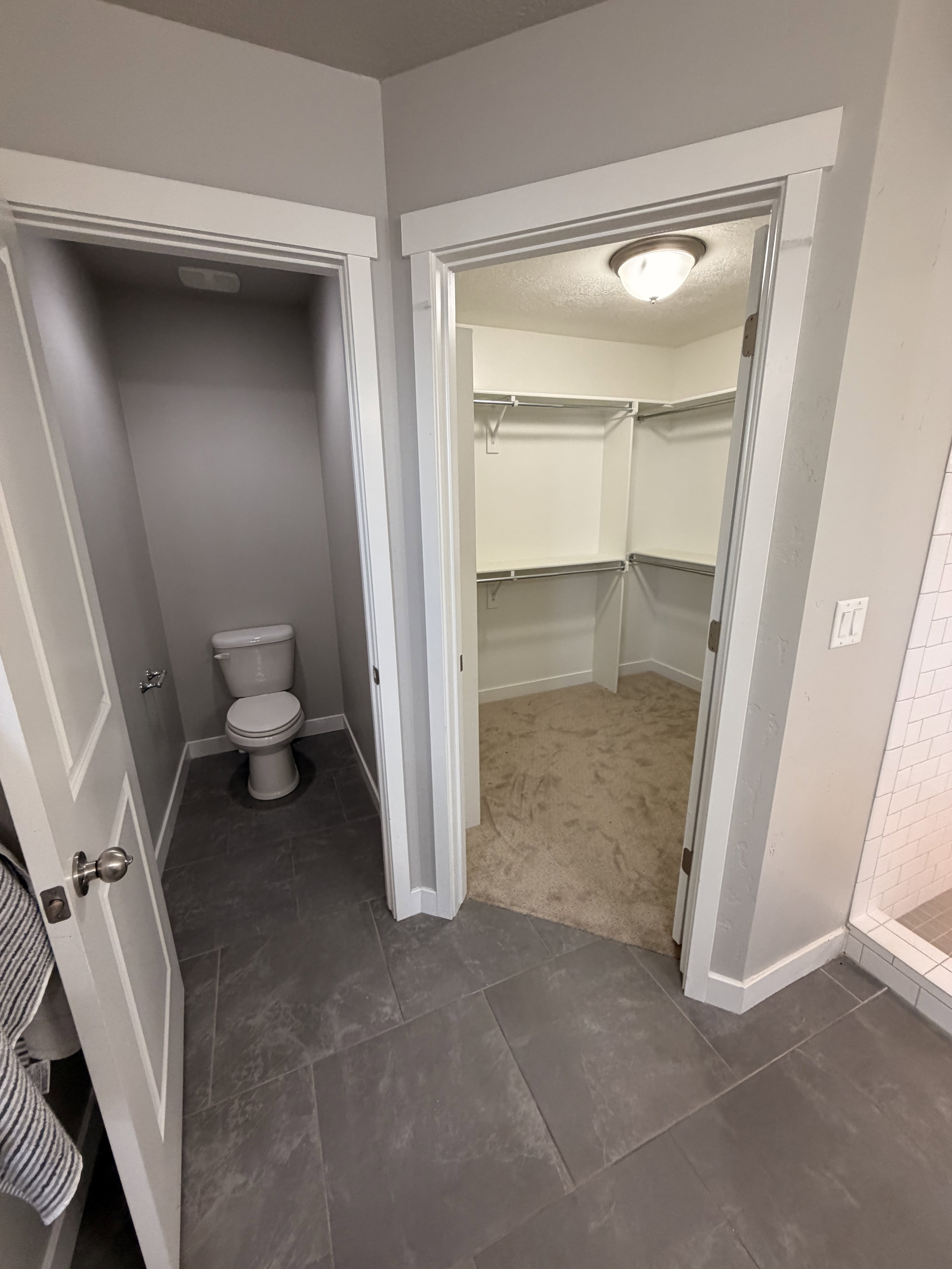 Dark gray tile flooring extending into a separate water closet