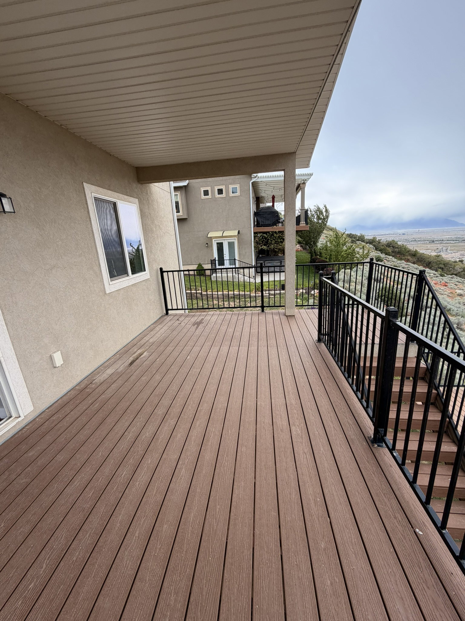 Expansive outdoor deck featuring wood-finish decking, black metal railings, and a covered ceiling