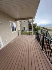 Expansive outdoor deck featuring wood-finish decking, black metal railings, and a covered ceiling