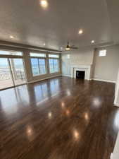 Expansive living area featuring rich wood-finish flooring, a contemporary fireplace with a decorative mantel, and a tray ceiling with recessed lighting