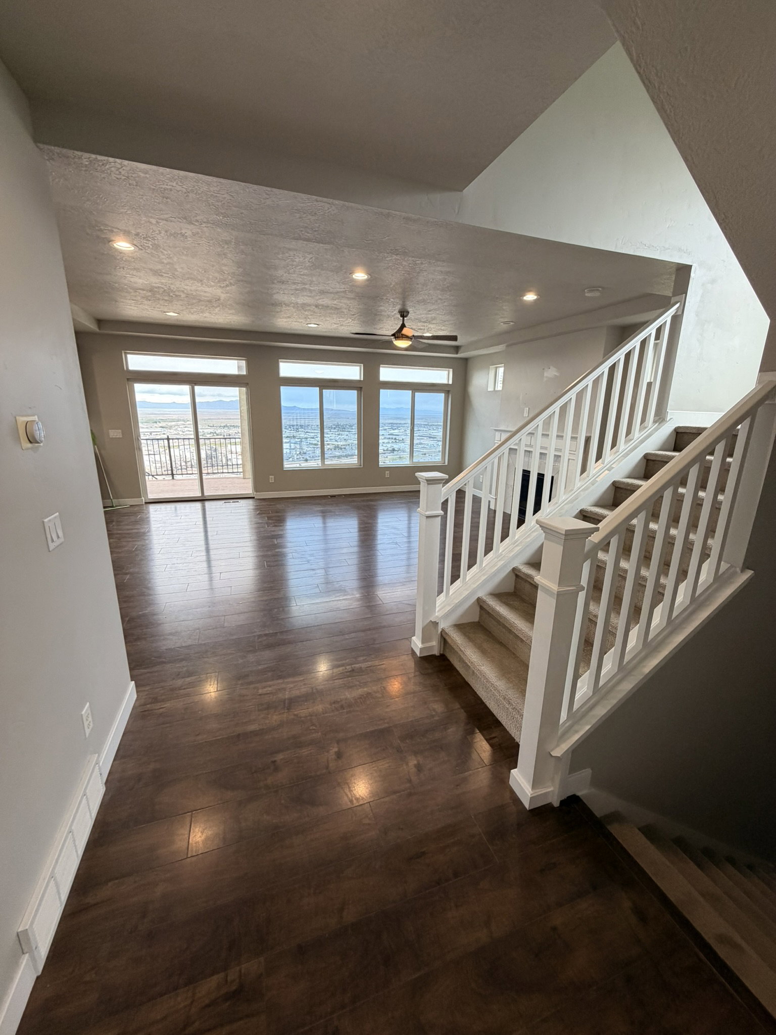 Open living area with wood-finish flooring and extensive window line
