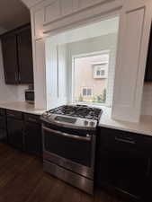 Stainless steel gas range with a tile backsplash and white countertops