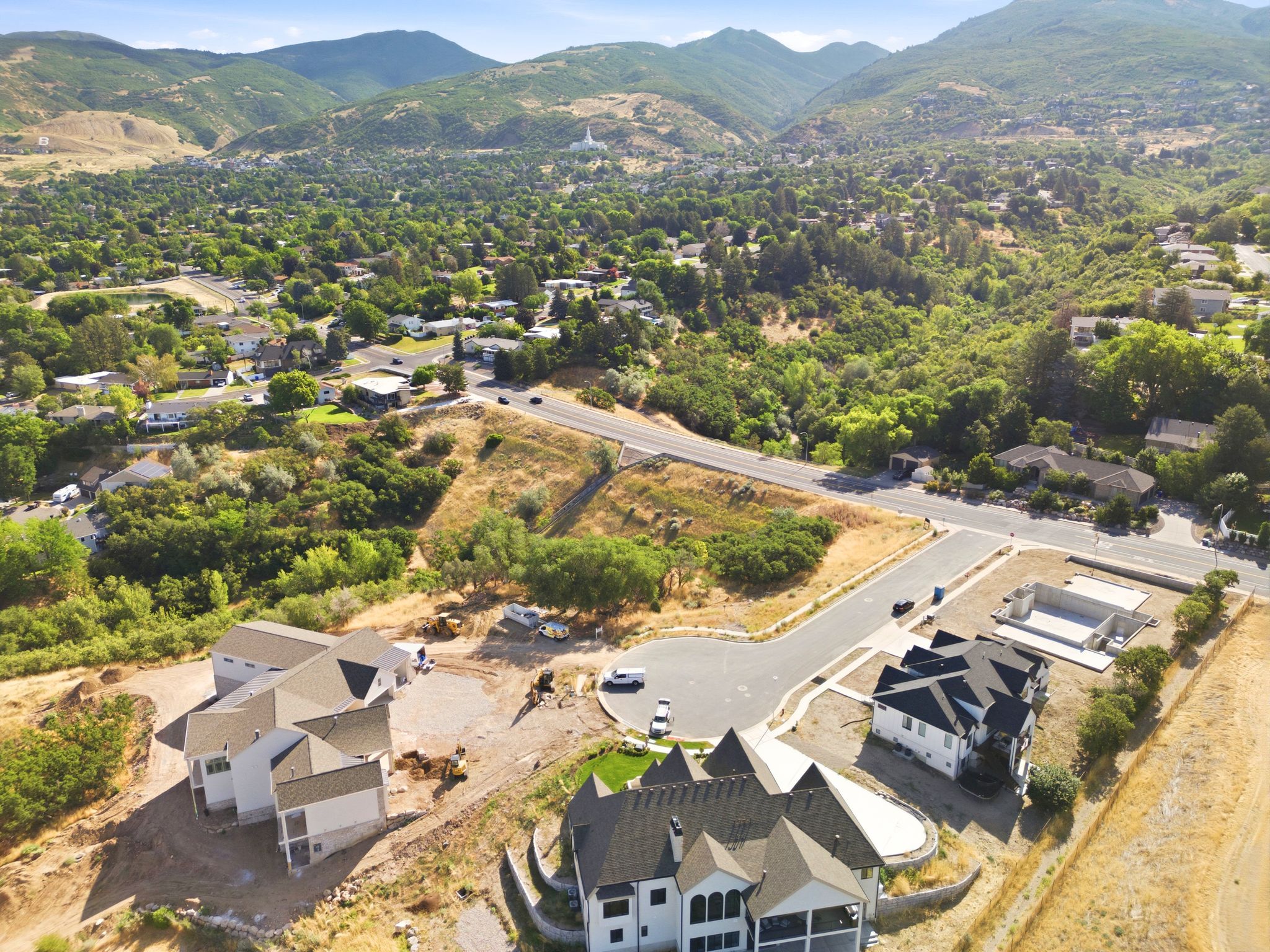 Aerial perspective showcasing properties under construction, surrounded by abundant green foliage and distant mountains