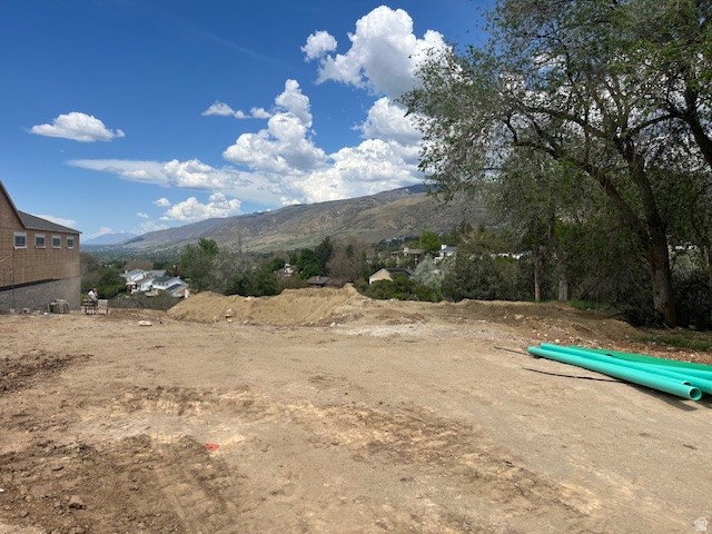 Cleared building lot featuring a mountainous backdrop and distant residential structures