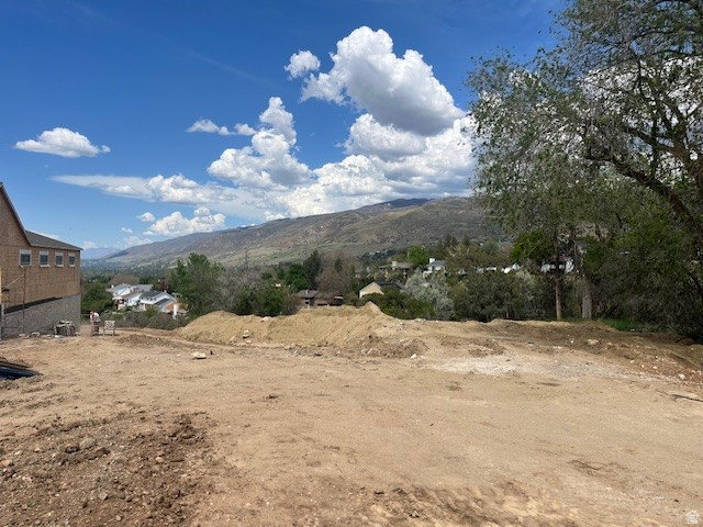 Expansive undeveloped lot featuring clear land, a partial brick structure, mountain backdrop, and scattered mature trees