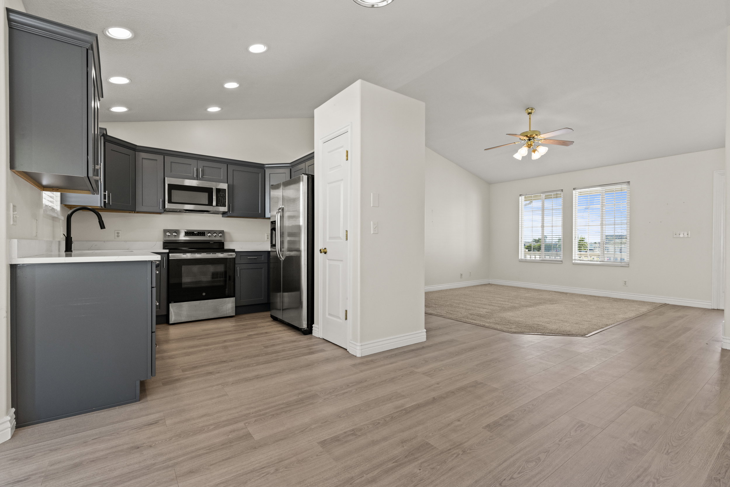 Spacious open concept layout featuring a kitchen with gray cabinetry, white countertops, and stainless steel appliances