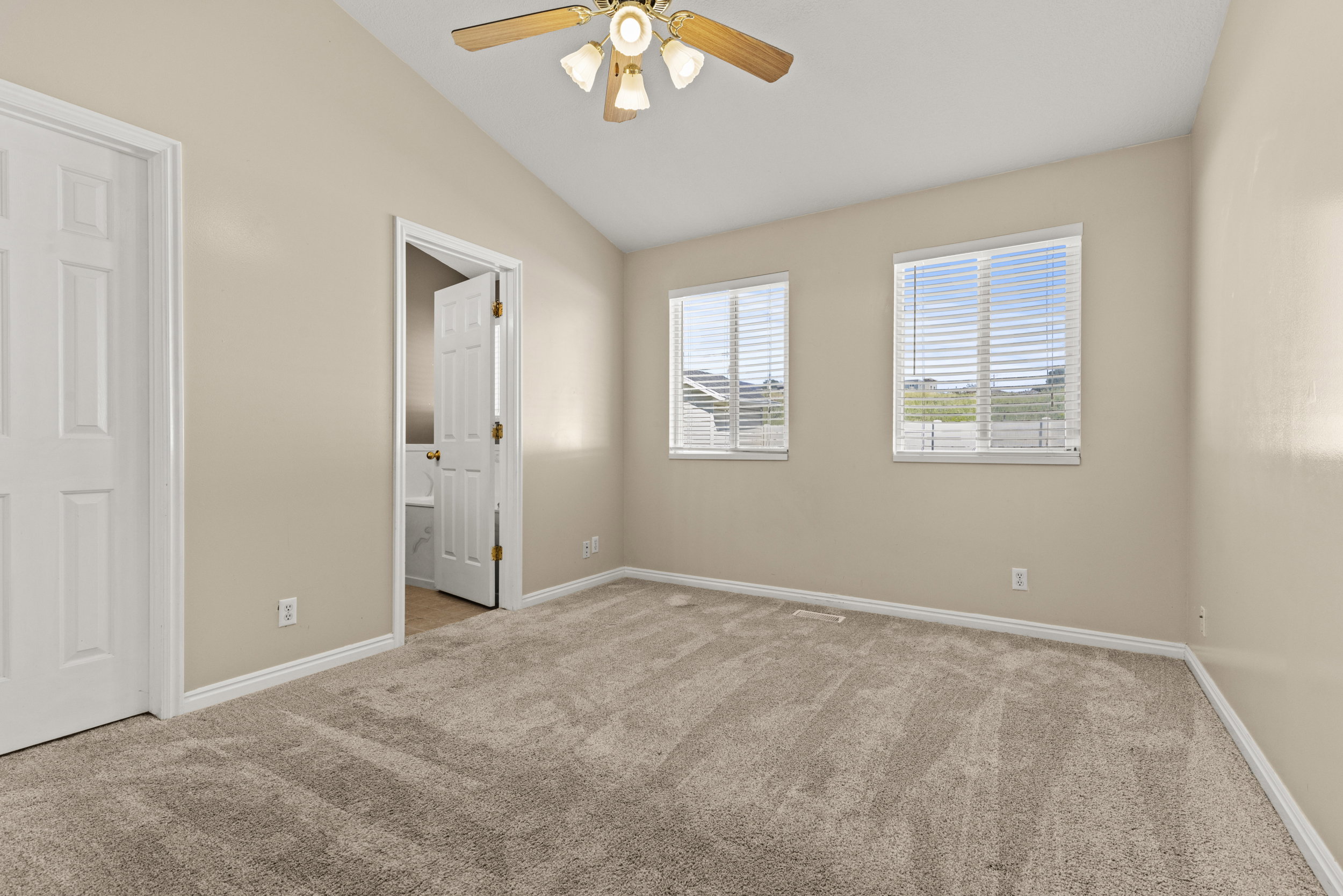 Carpeted room with a vaulted ceiling and a ceiling fan light fixture